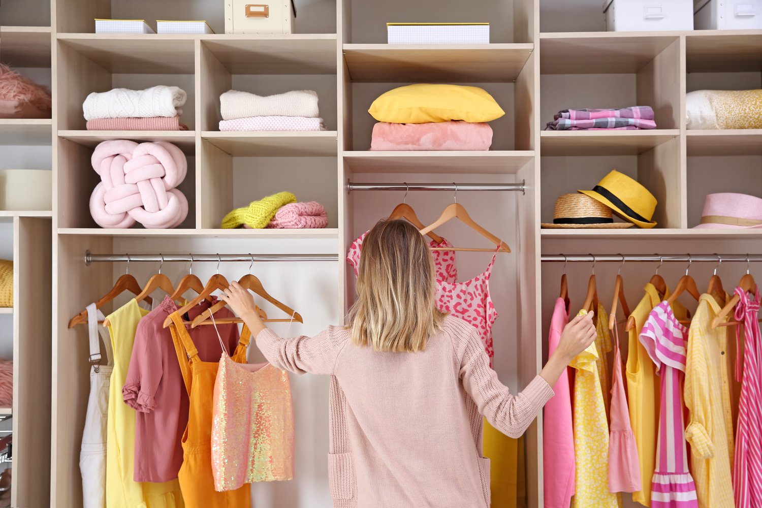 Photo of woman choosing clothes from large wardrobe closet