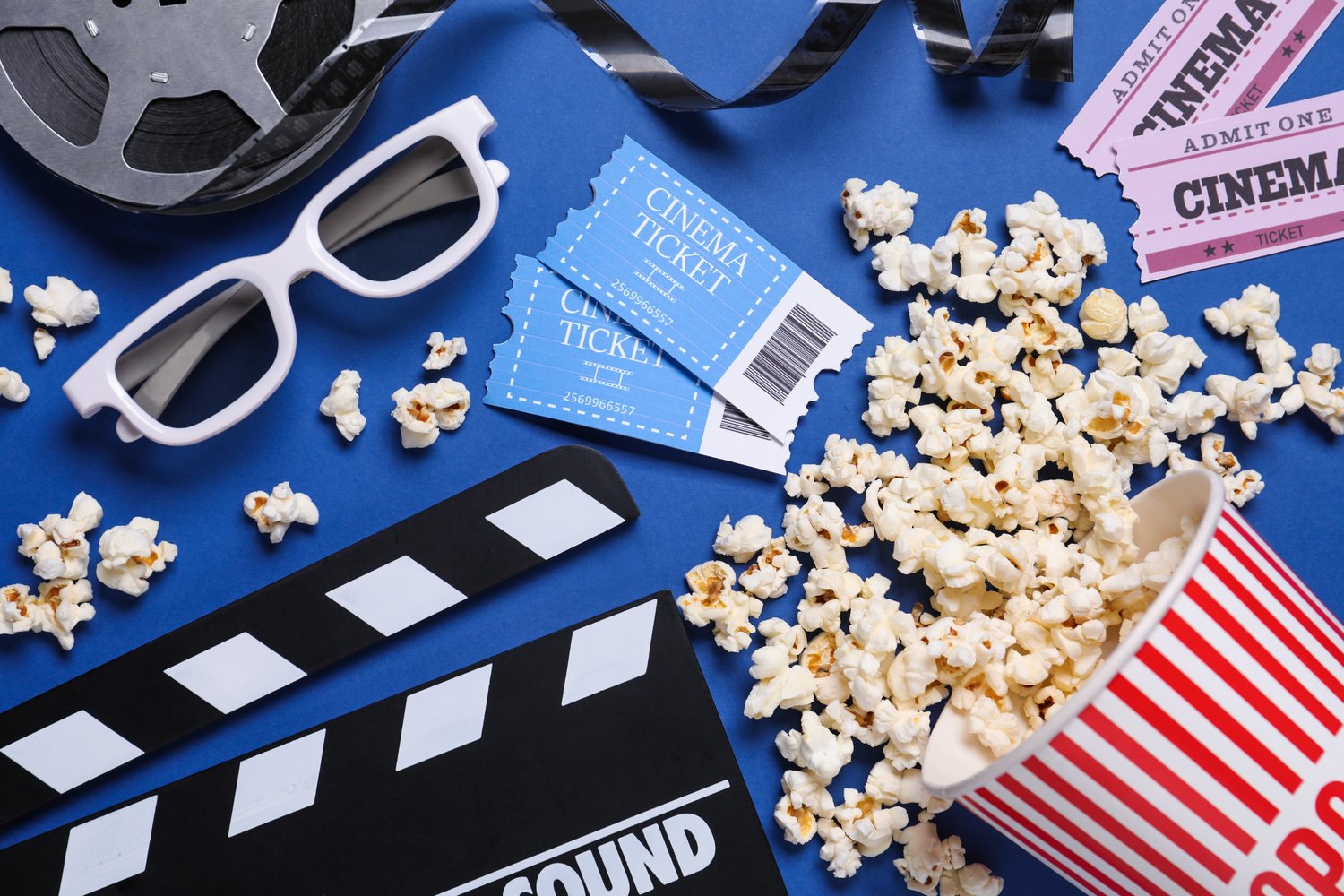 Photo of flat lay composition with clapperboard, cinema tickets and 3d glasses on blue background