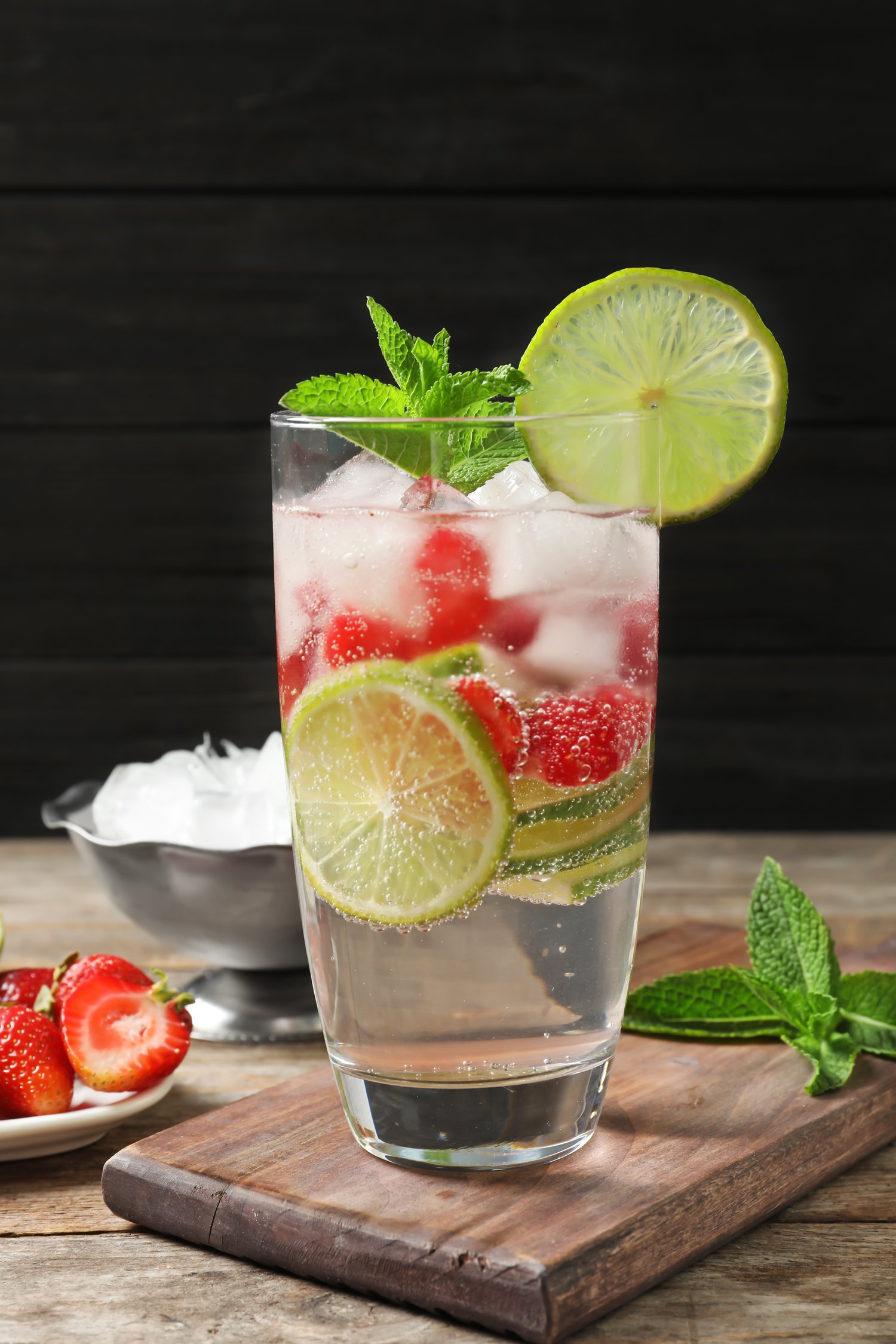 Photo of glass of natural lemonade with lime, strawberries and mint on table