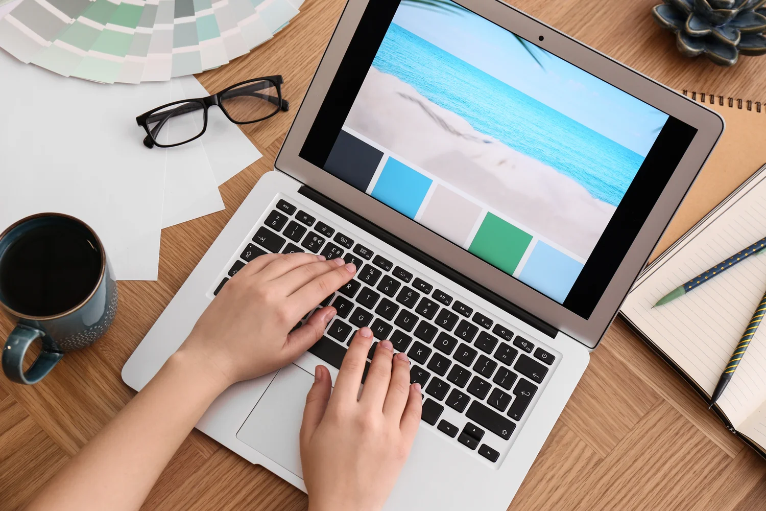Photo of designer working on laptop at wooden table, above view