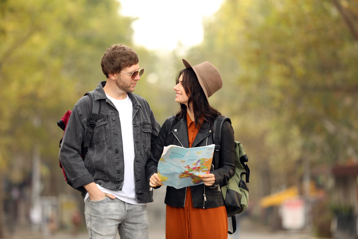 Photo of couple of travelers with map on city street