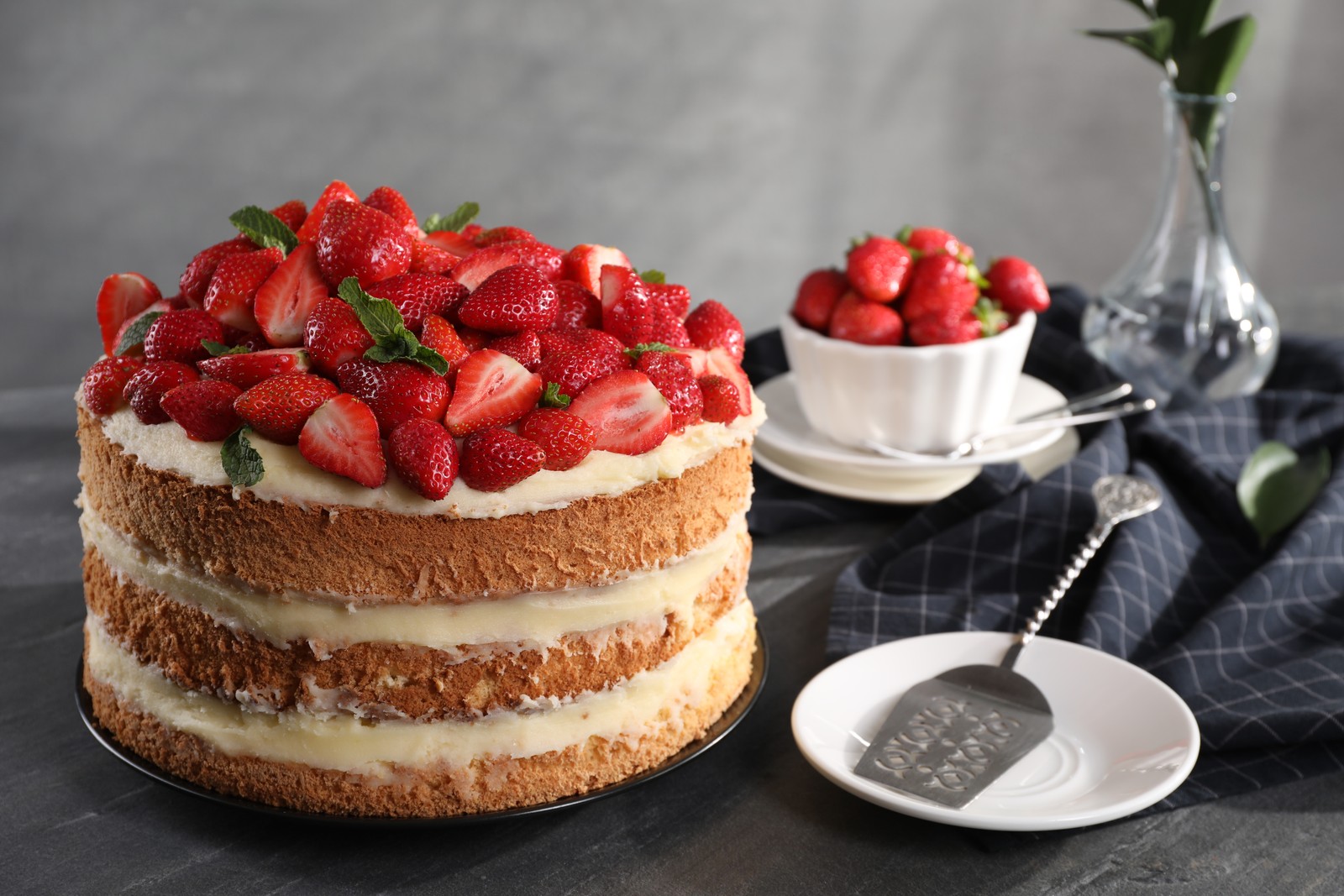 Photo of tasty cake with fresh strawberries and mint served on gray table
