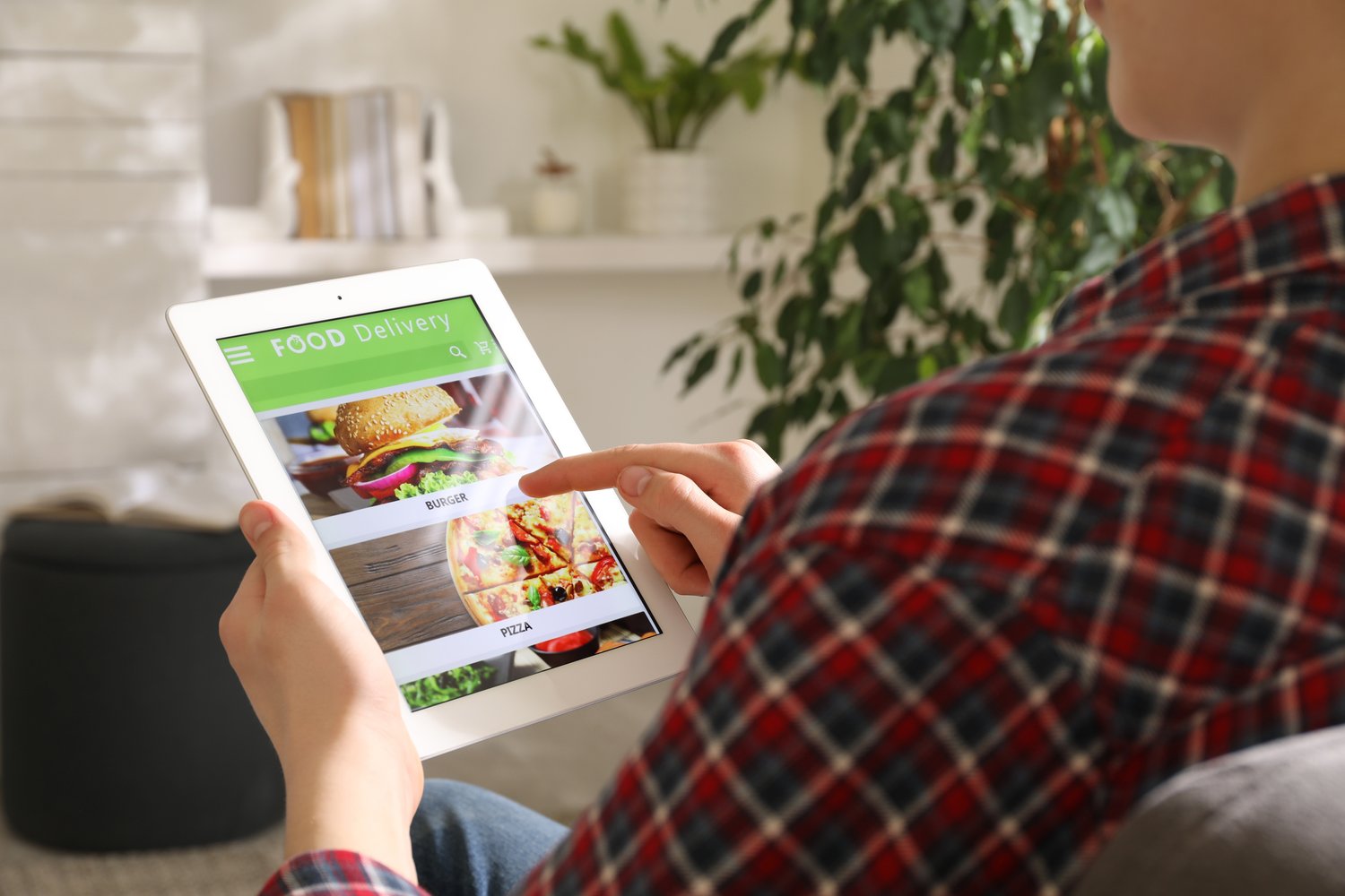 Photo of man using tablet for ordering food online at home, closeup. Delivery service