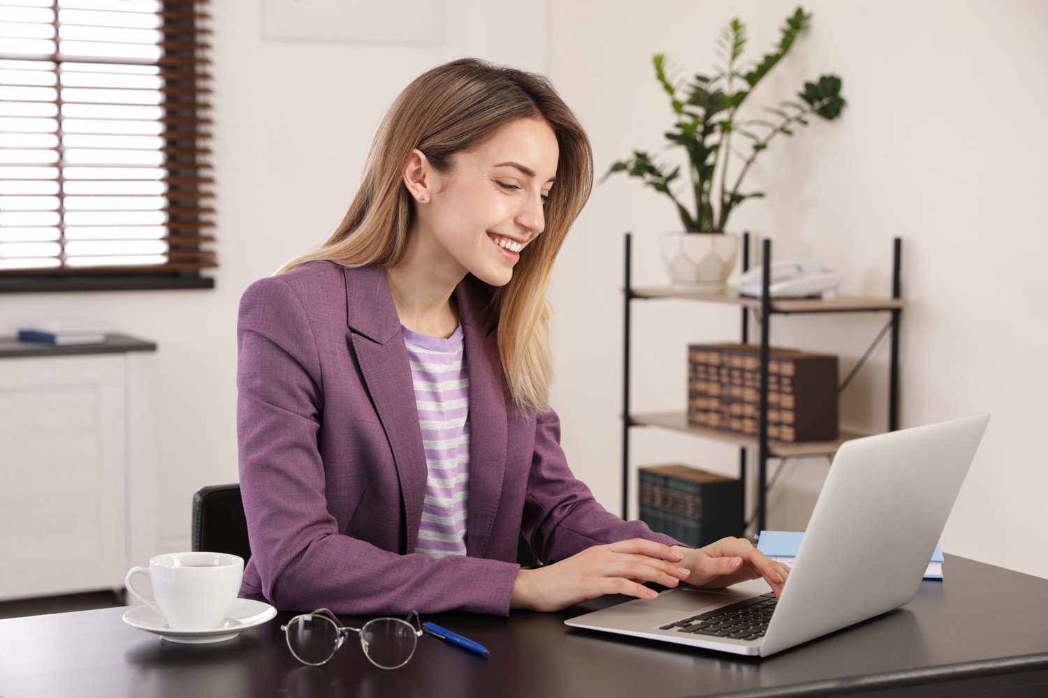 Photo of young woman working on laptop in office