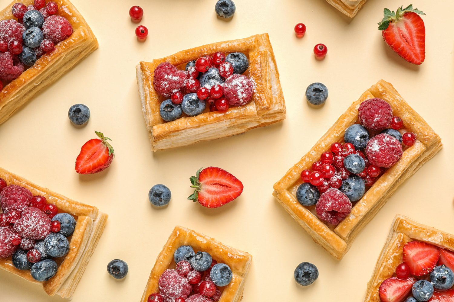 Photo of fresh delicious puff pastry with sweet berries on beige background, flat lay