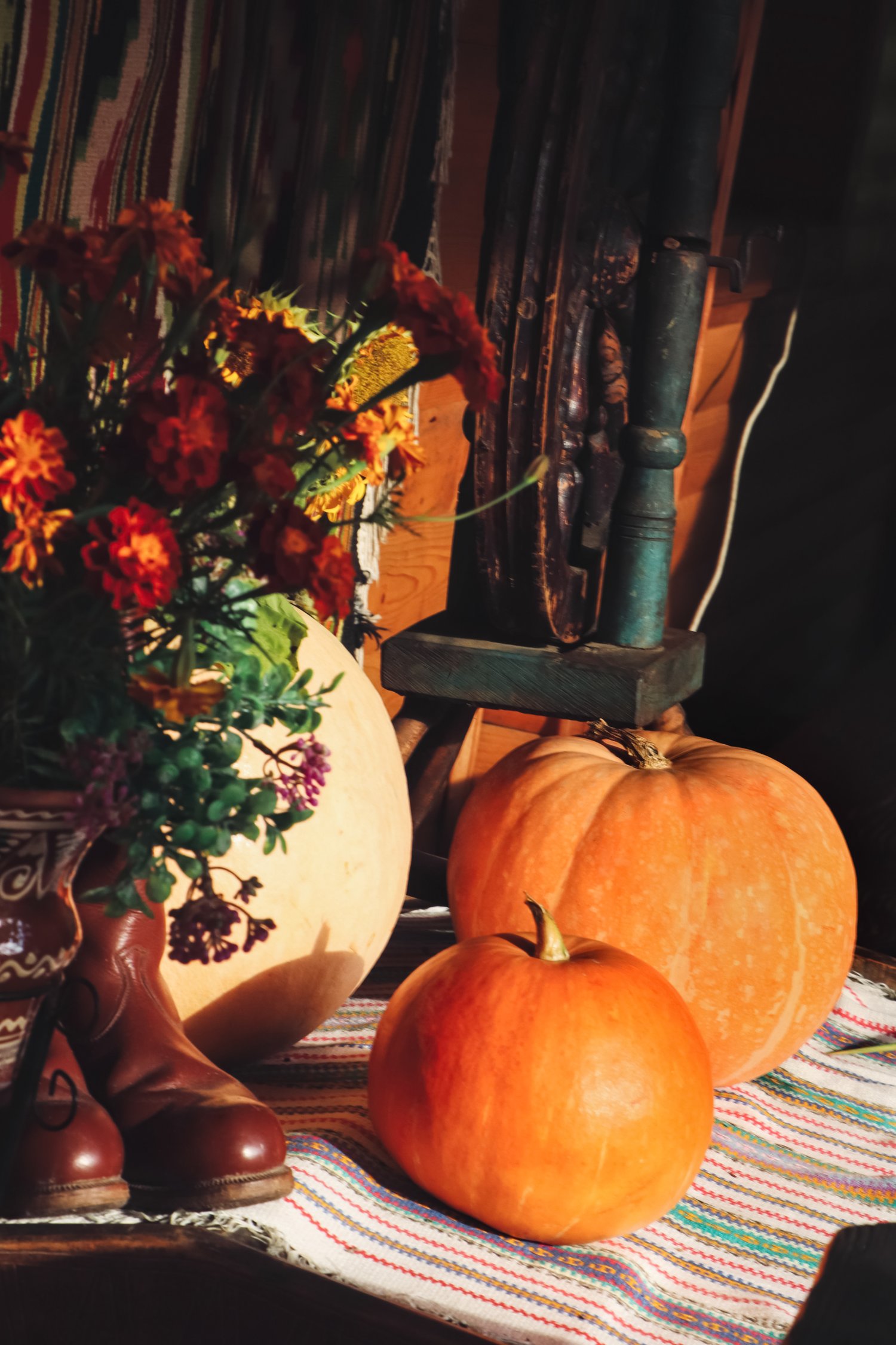 Photo of beautiful bouquet, pumpkins and boots on table indoors
