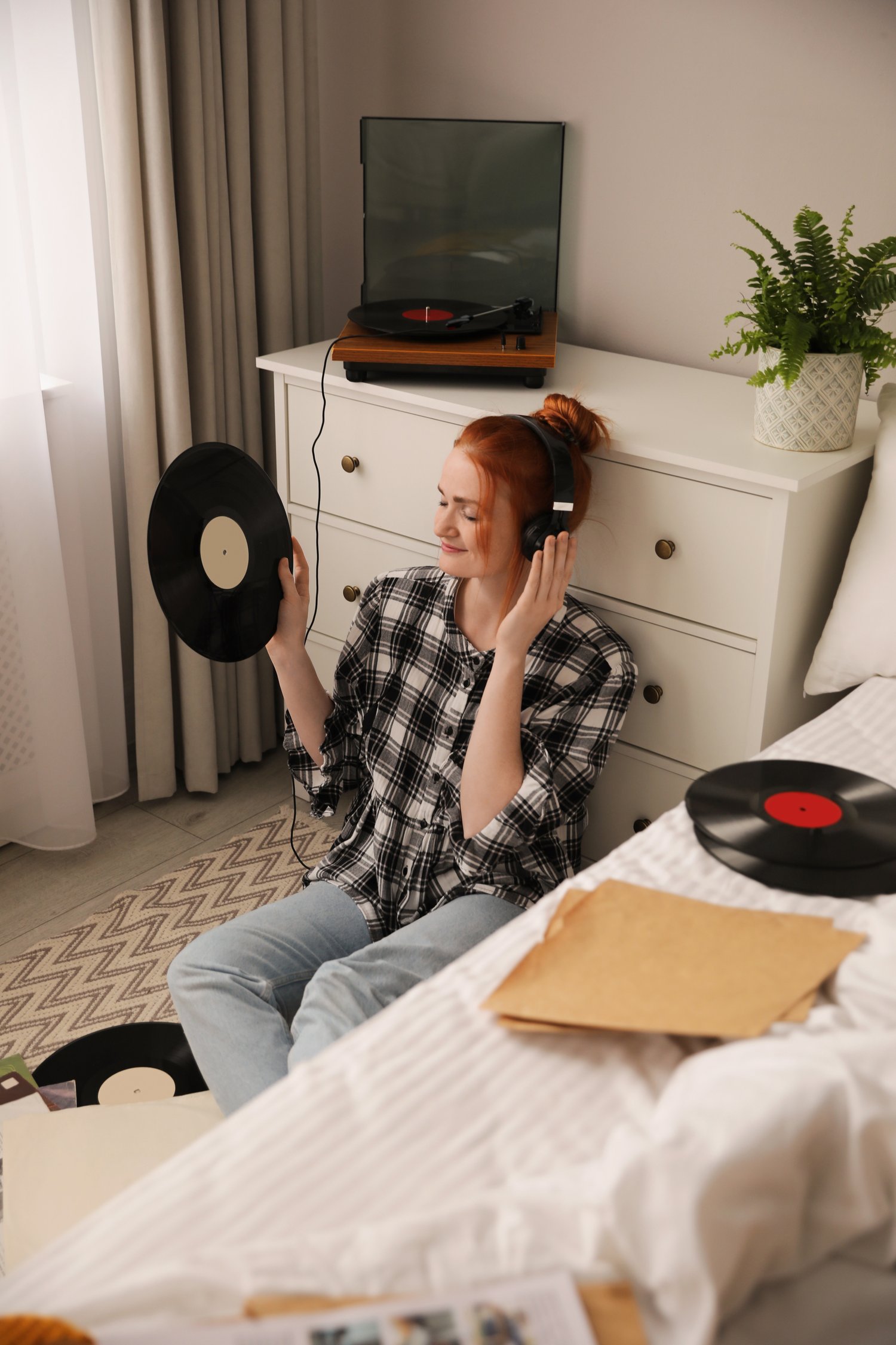 Photo of young woman listening to music with turntable in bedroom