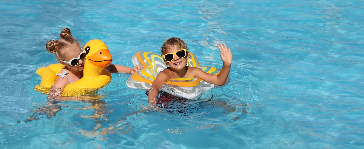 Photo of happy children with inflatable rings in outdoor swimming pool on sunny summer day