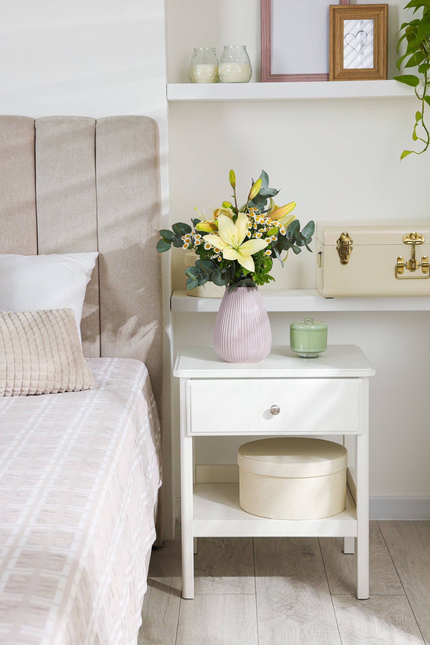 Photo of bouquet of beautiful flowers on nightstand in bedroom