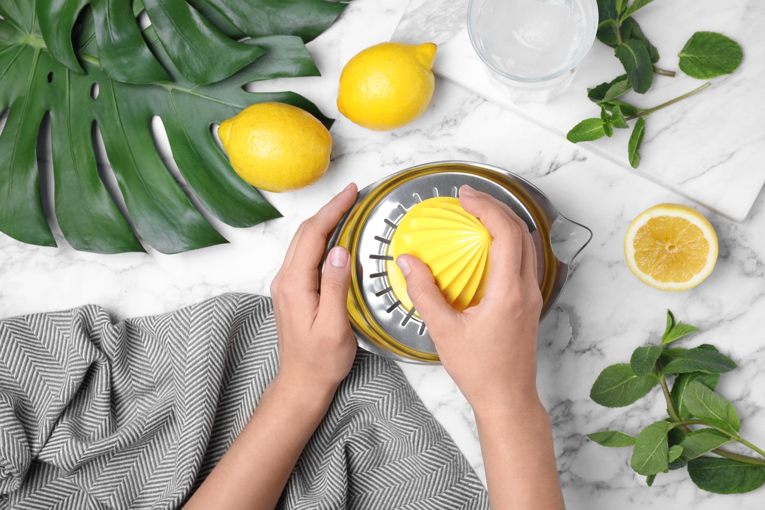 Photo of woman with squeezer and ingredients for lemonade at marble table, top view