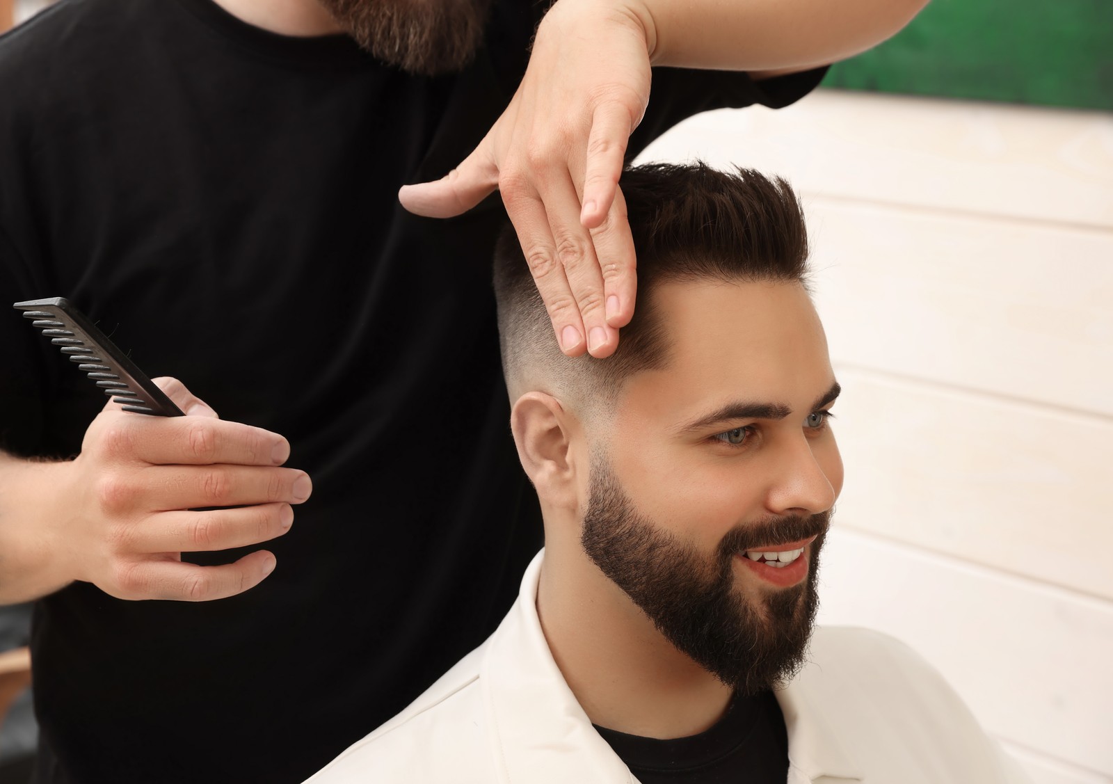 Photo of professional hairdresser working with client in barbershop, closeup