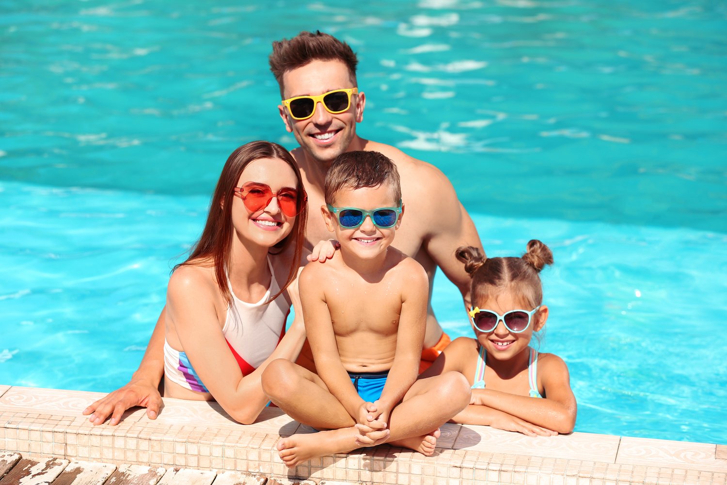 Photo of happy family in swimming pool on sunny day