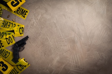 Photo of Flat lay with yellow tape, crime scene marker and gun on grey stone background. Space for text
