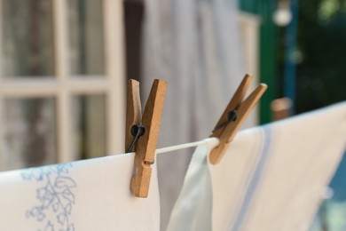 Photo of Washing line with clean laundry and clothespins outdoors, closeup. Space for text