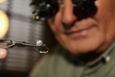 Photo of Professional jeweler working with beautiful ring indoors, closeup