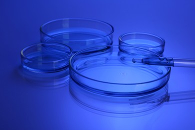 Photo of Dripping liquid into Petri dish on table, toned in blue