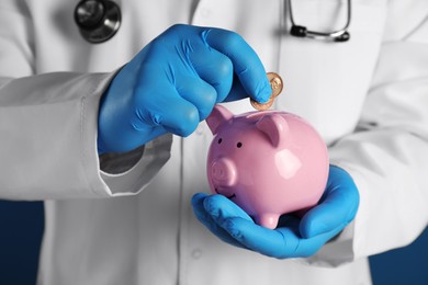 Photo of Doctor putting coins into piggy bank, closeup. Medical insurance