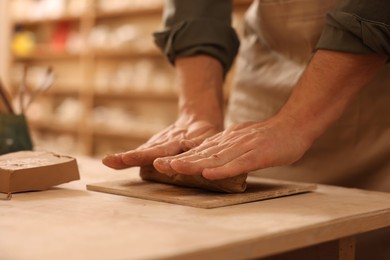 Photo of Man crafting with clay at table indoors, closeup