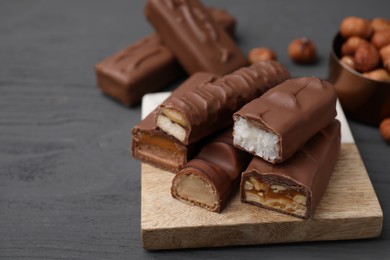 Photo of Pieces of different tasty chocolate bars on grey wooden table, closeup. Space for text