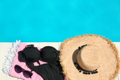 Photo of Beach accessories on wooden deck near swimming pool, flat lay. Space for text