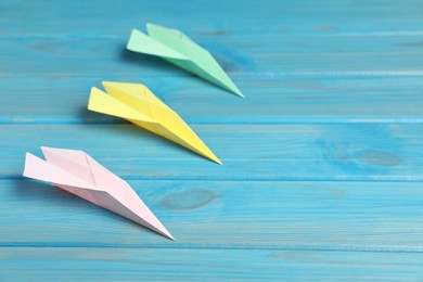 Photo of Handmade paper planes on light blue wooden table. Space for text