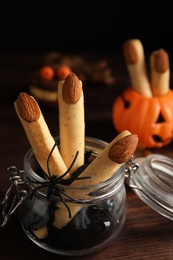 Photo of Delicious desserts decorated as monster fingers on wooden table. Halloween treat