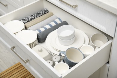 Photo of Open drawerkitchen cabinet with different dishware and towels