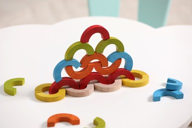 Photo of Colorful wooden pieces of playing set on white table indoors. Educational toy for motor skills development