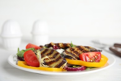 Photo of Delicious salad with roasted eggplant served on white wooden table, closeup
