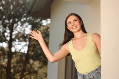 Photo of Neighbor greeting. Happy woman waving near house outdoors