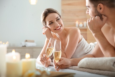 Photo of Romantic young couple with champagne in spa salon