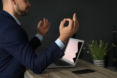 Photo of Businessman practicing zen yoga at table in office, closeup