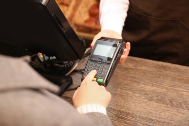 Photo of Woman using payment terminal at shop, closeup