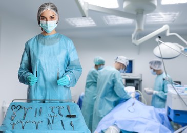 Image of Nurse near table with different surgical instruments in operating room