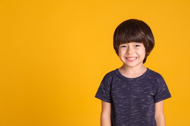 Photo of Portrait of cute little boy on yellow background, space for text