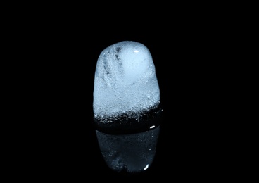 Photo of Melting ice cube on black background. Frozen liquid