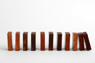 Photo of Wooden domino tiles falling on white background. Space for text