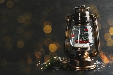Image of Beautiful Christmas snow globe in vintage lantern on grey background, bokeh effect. Space for text
