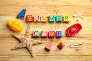 Photo of Flat lay composition with phrase SUMMER CAMP made of colorful cubes on wooden background