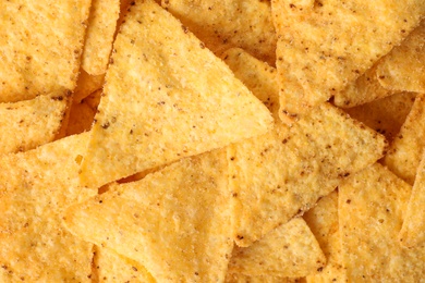 Photo of Tasty Mexican nachos chips as background, top view