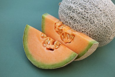 Photo of Whole and cut fresh ripe cantaloupe melons on teal background, closeup