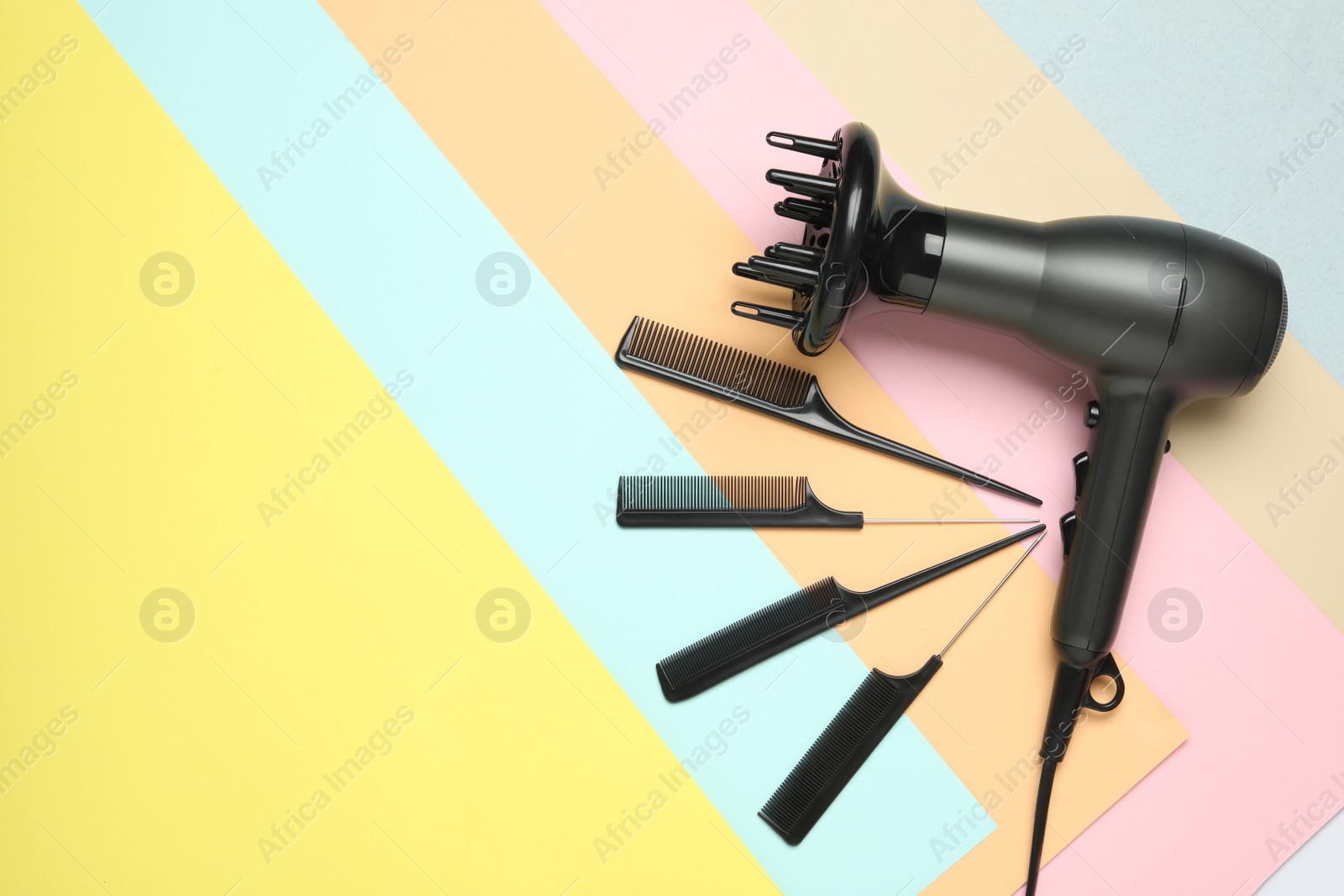 Photo of Hair dryer and different combs on color background, flat lay. Professional hairdresser tool