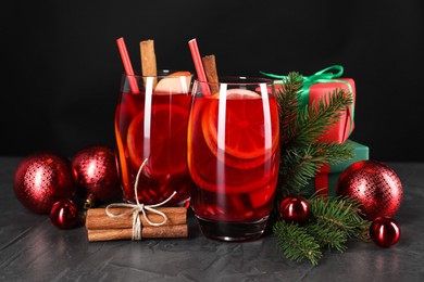Photo of Delicious Sangria drink in glasses and Christmas decorations on dark textured table, closeup