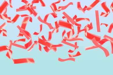 Image of Bright red confetti falling on gradient light blue background