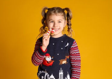 Photo of Cute little girl with Christmas gingerbread cookie on yellow background