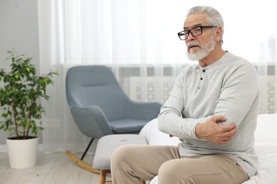 Photo of Arthritis symptoms. Man suffering from pain in elbow at home