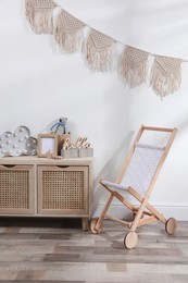 Photo of Drawer unit and wooden buggy indoors. Children's room interior