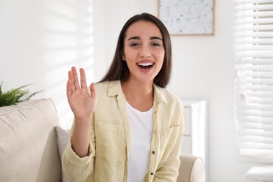 Photo of Young woman talking with her coworkers on video call indoors, view from web camera
