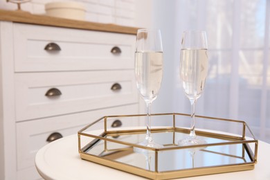 Photo of Tray with two glasses of delicious sparkling wine on white table indoors. Valentine Day celebration