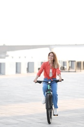 Young woman riding bicycle in city on sunny day